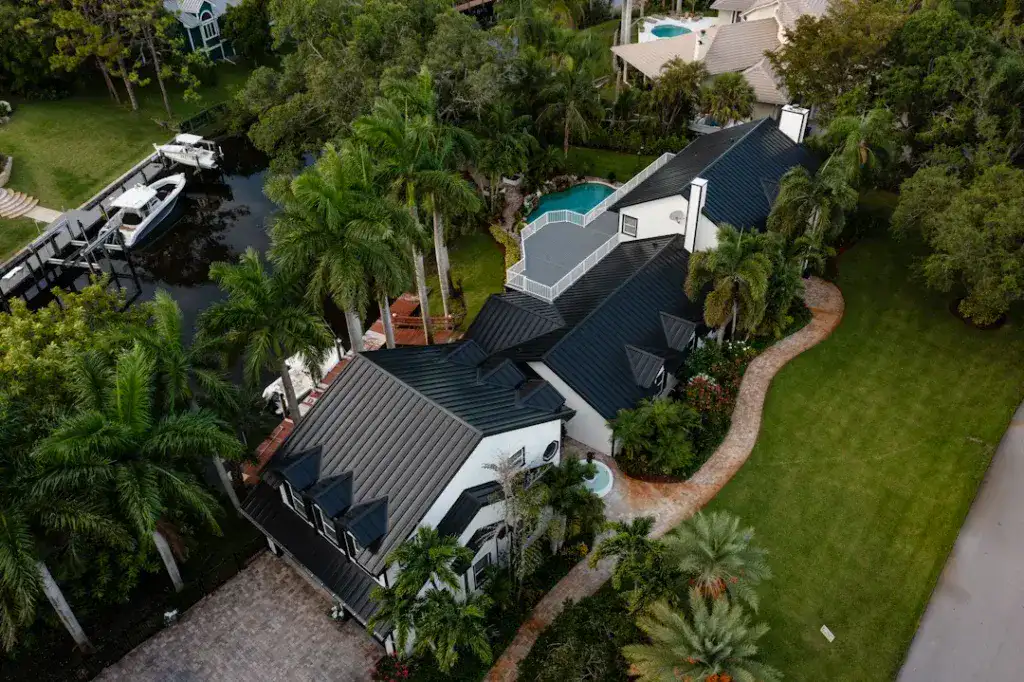 Aerial view of a waterfront home with a black standing seam metal roof by All-Type Roofing Services