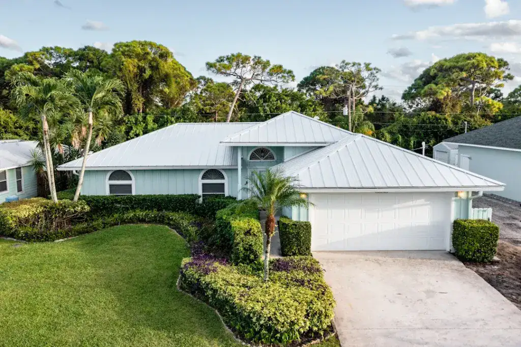 Home with a new white metal roof installed by All-Type Roofing Services